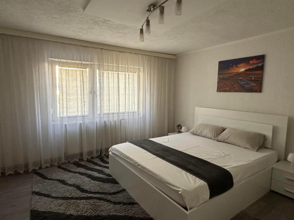 a bedroom with a white bed and a window at Guesthouse Mema in Sarajevo