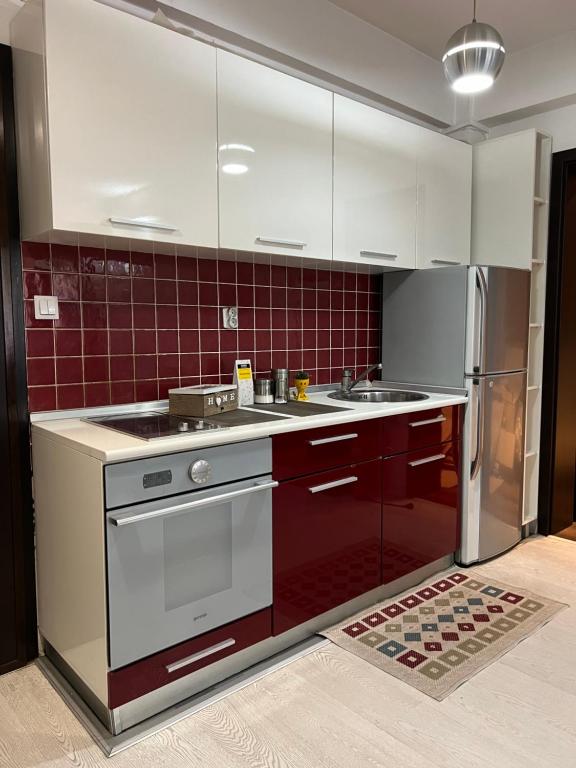 a kitchen with red and white cabinets and a refrigerator at Reina Apartments Skopje 3 in Skopje