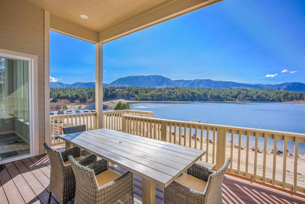 a table and chairs on a balcony with a view of the water at Luxury Lake House With Mountain Views & Hot Tub in Monument