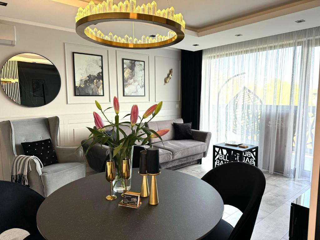 uma sala de estar com uma mesa e um lustre em Apartamenty Blue Baltic Chłopy nad morzem em Chłopy