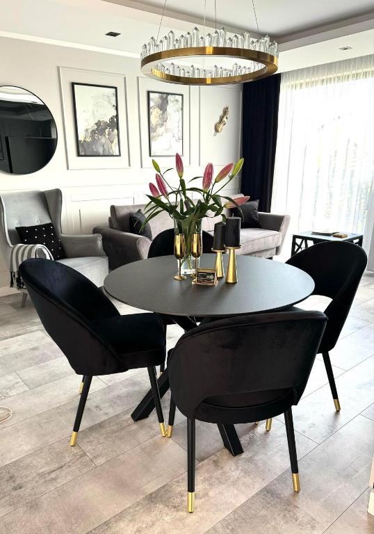 a dining room with a black table and chairs at Apartamenty BLUE BALTIC SPA Jacuzzi & Sauna MORZE in Chłopy