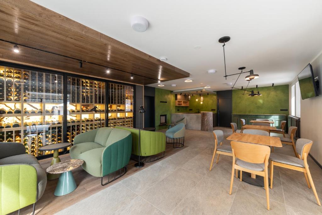 un restaurante con sillas verdes, mesas y botellas de vino en Resort - D9, en Želnava