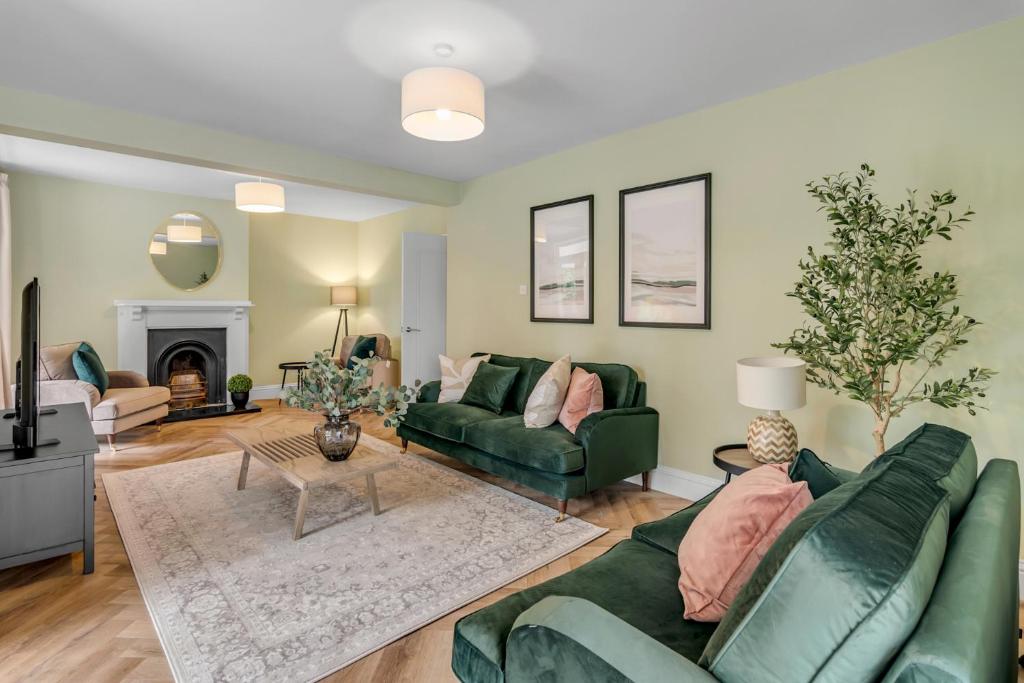 a living room with green furniture and a fireplace at Stunning coastal 6/bed house w/parking & garden in Cromer