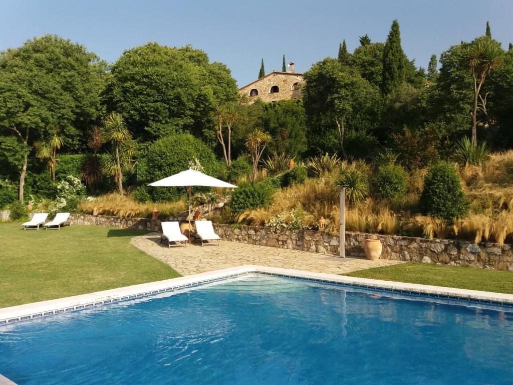 een zwembad in een tuin met stoelen en een parasol bij Can Serola in Sales del Llierca