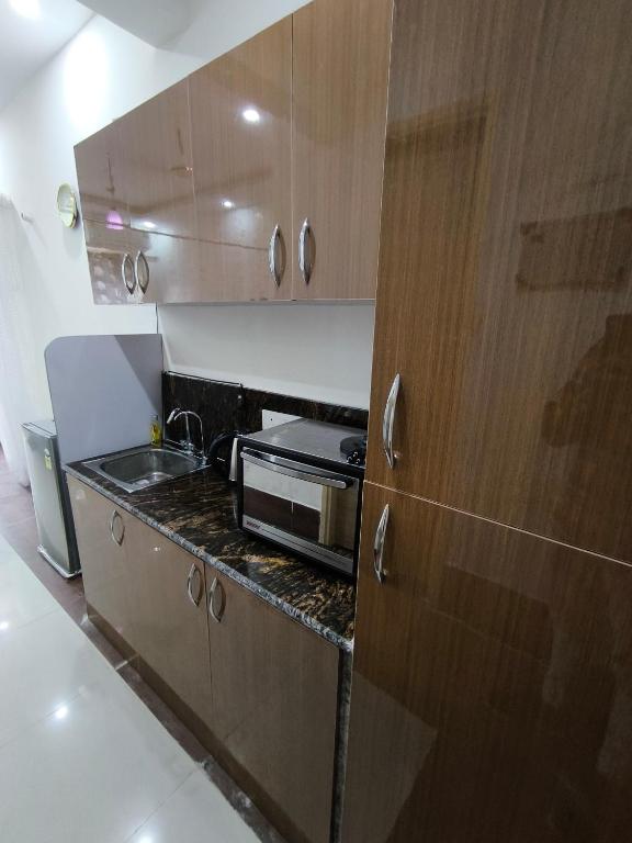 een keuken met houten kasten en een wastafel bij Vision Studio Apartment in Ghaziabad