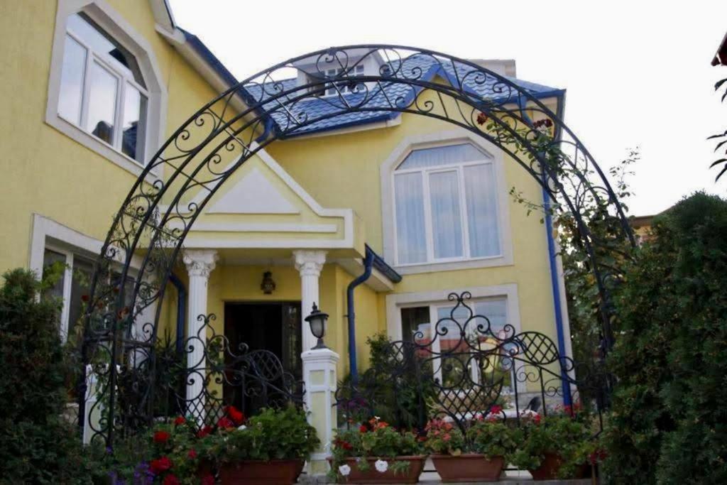 une maison jaune avec une porte en fer et des fleurs dans l'établissement District One Villa with Private Courtyard and Terrace, à Bucarest