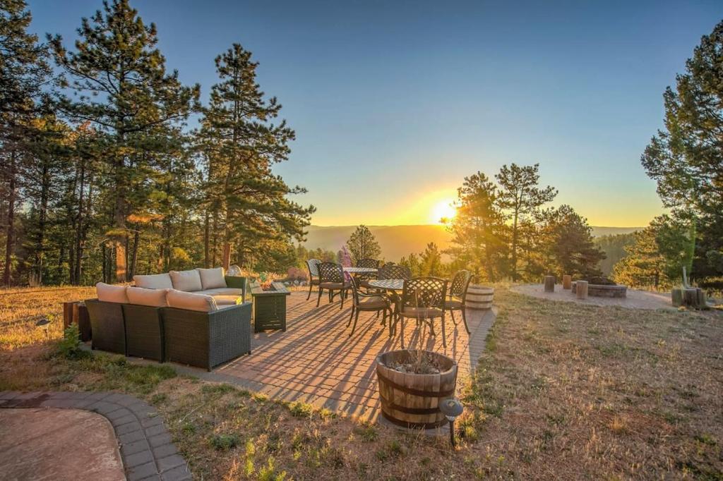 a patio with a couch and a table and chairs at 5BR Family Mountain Cabin Hot Tub & Gaming Garage in Woodland Park