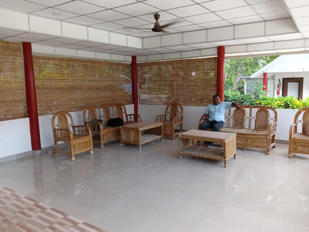 a man sitting in a room with chairs and tables at Neil Holiday Resort in Neil Island