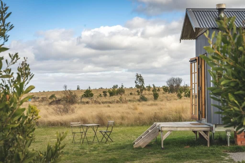 ein Haus mit einem Picknicktisch und Stühlen auf einem Feld in der Unterkunft Altitude - A Tiny House Experience in a Goat Farm in Romsey