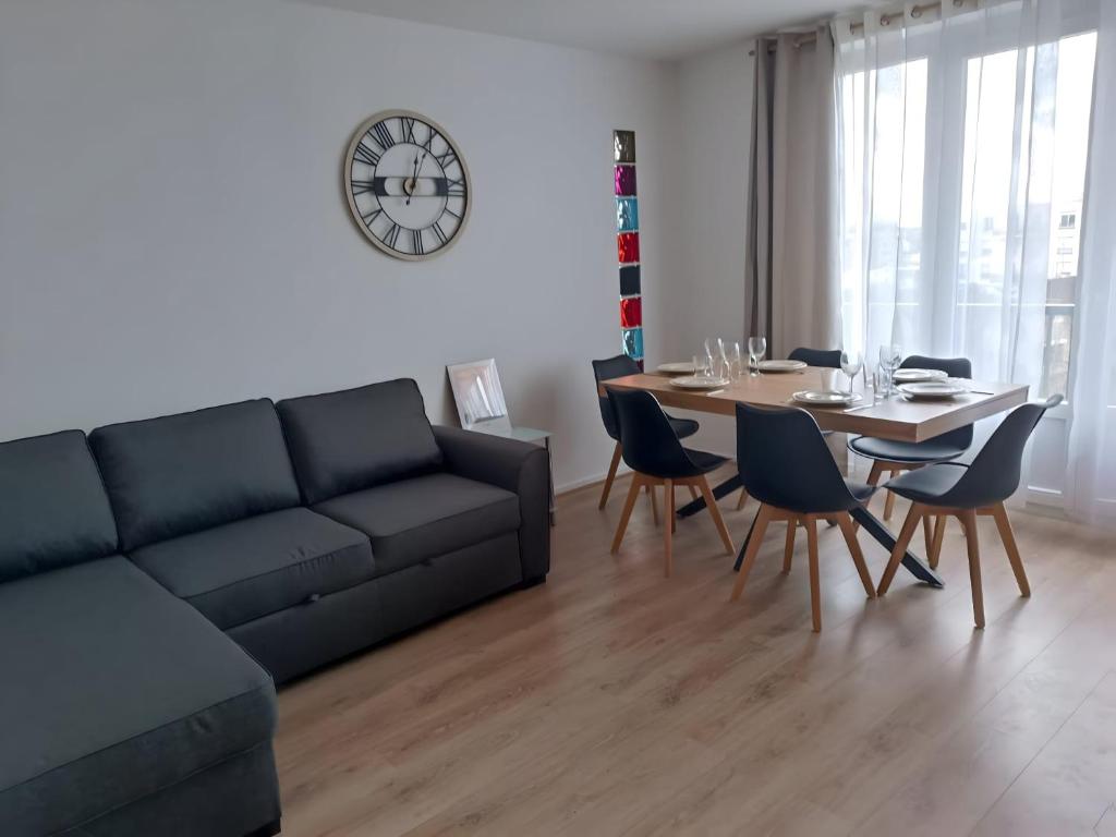 een woonkamer met een bank en een tafel met stoelen bij Appartement proche PARIS/STADE DE FRANCE in Épinay-sur-Seine