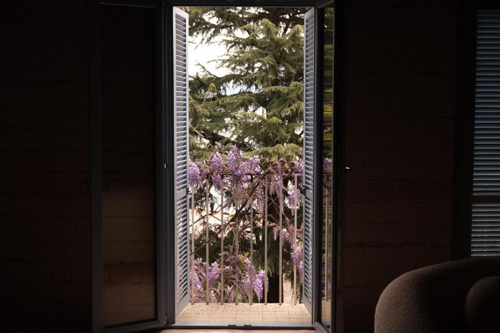 une porte ouverte sur un jardin avec des fleurs violettes à l'extérieur dans l'établissement Rooms Hotel Batumi, à Batoumi