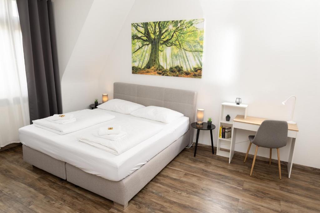 a bedroom with a bed and a desk and a painting at BeMyGuest - 3 Zimmer Maisonette - Zentral - Klimaanlage - Aufzug in Wiesbaden