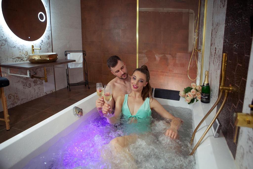 un hombre y una mujer en una bañera con una copa de vino en La Vie - Apartmány, en Telč