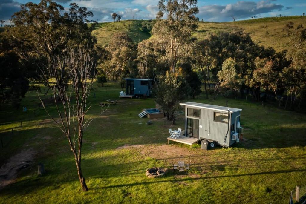 RV zaparkowany na polu obok drzew w obiekcie Tiny House Farmstay at Dreams Alpaca Farm - A Windeyer Outback Experience w mieście Windeyer