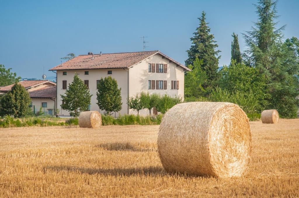 un campo di balle di fieno di fronte a una casa di Agriturismo Casella Del Piano a Gubbio