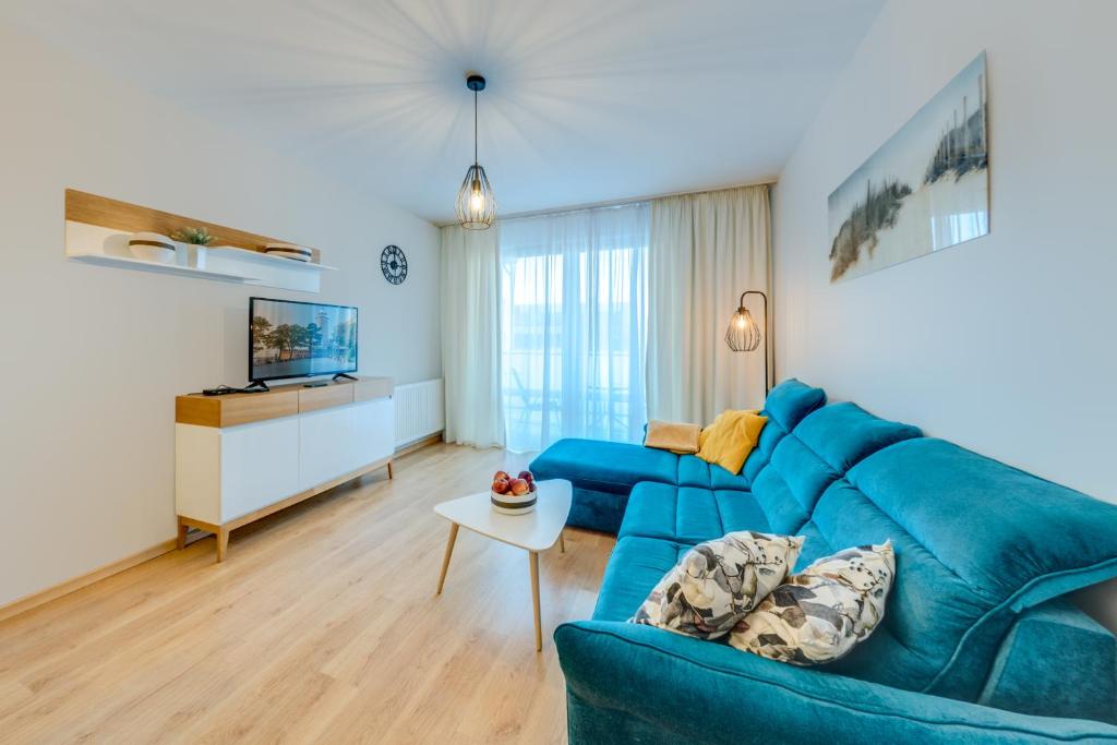 a living room with a blue couch and a tv at Aquarius Apartament 115 - 4 piętro widok w stronę morza in Kołobrzeg