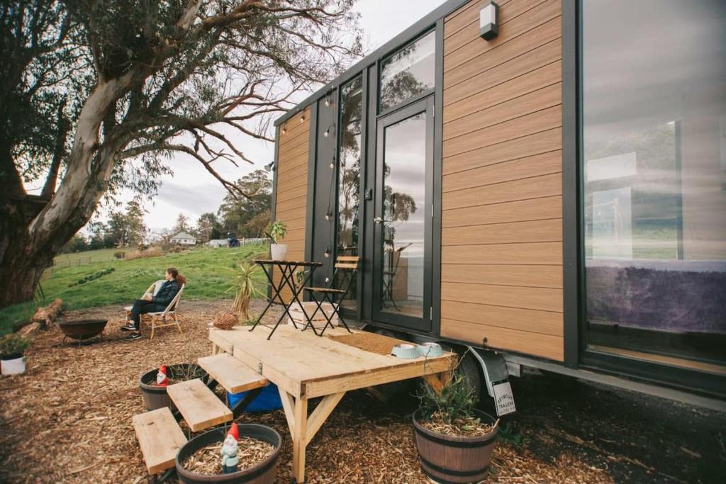 a tiny house with a man sitting in a chair at Rose Hill in Neerim South