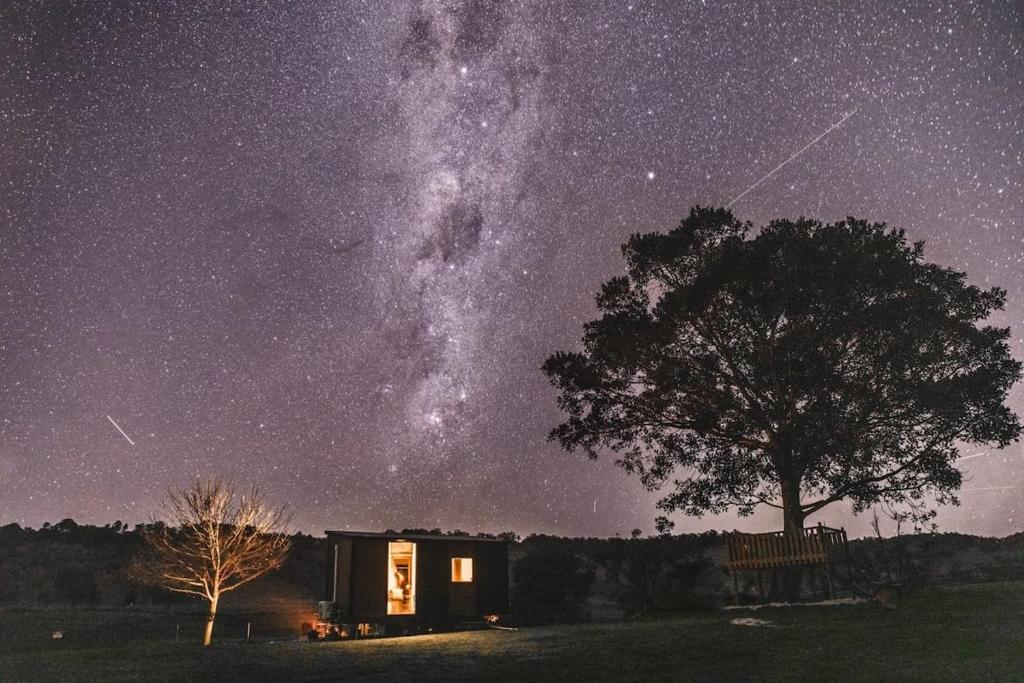 a cabin with a tree and the milky way at On the Rocks in Lismore