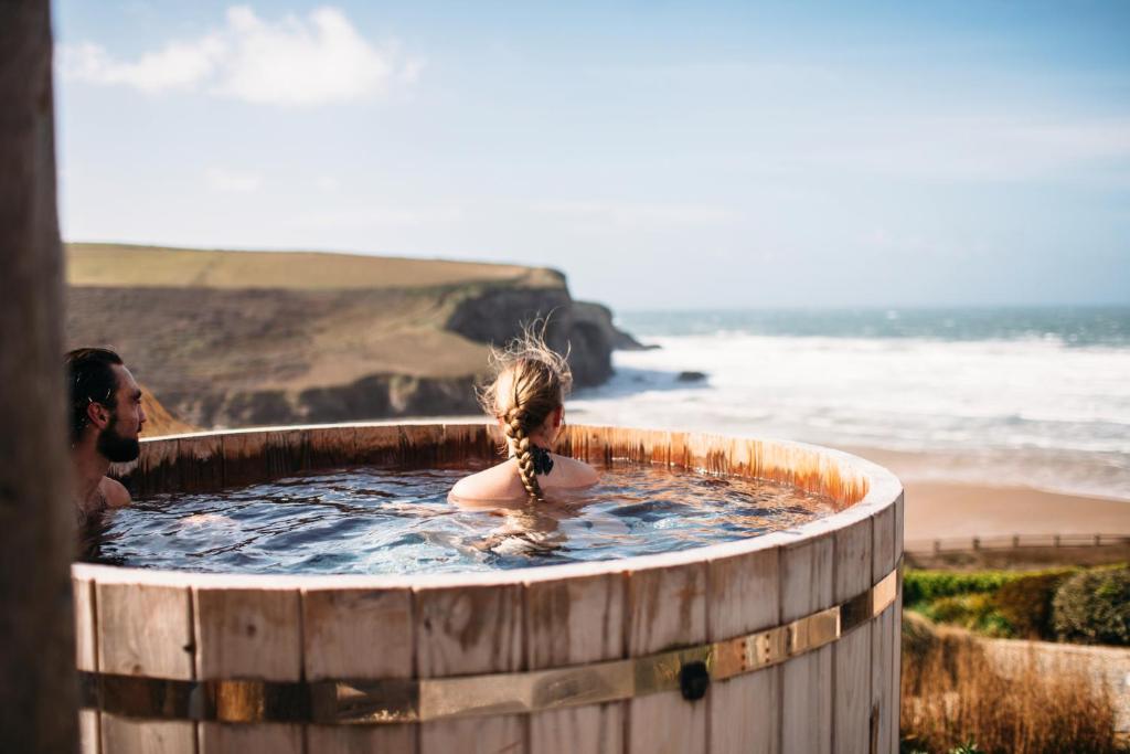 a man and a girl in a hot tub near the beach at The Scarlet Hotel in Mawgan Porth