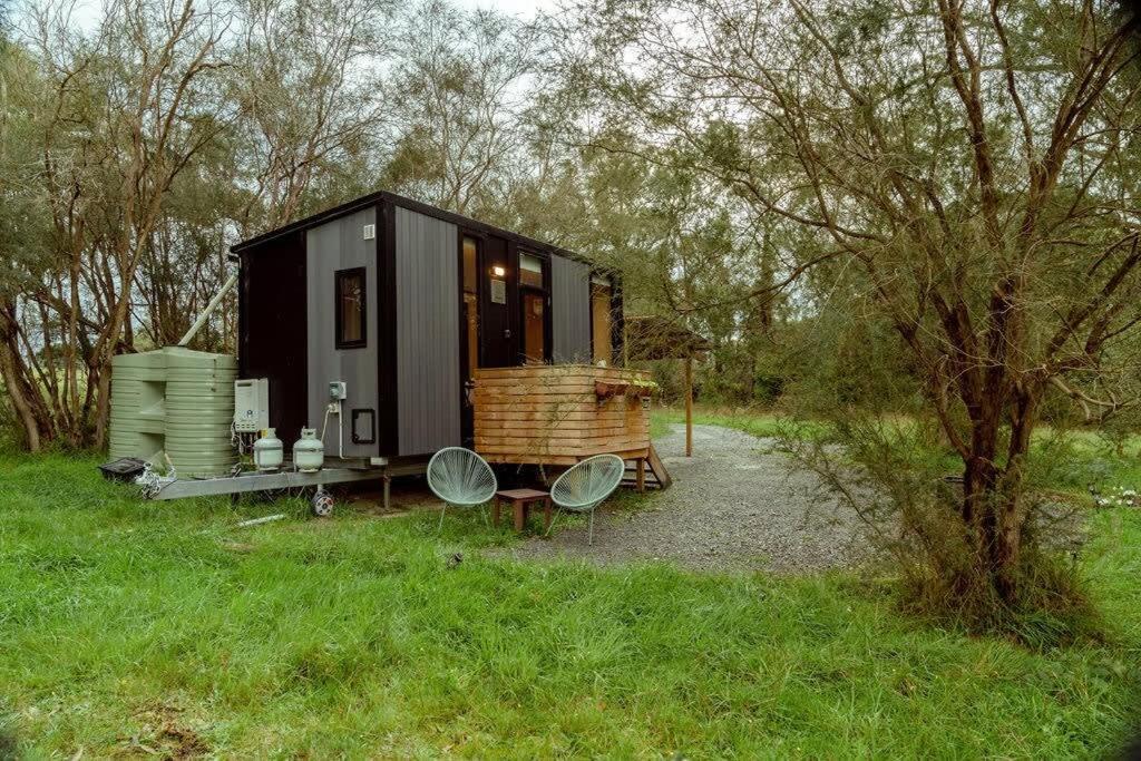 a black tiny house sitting in a field at Prunus Hideaway 