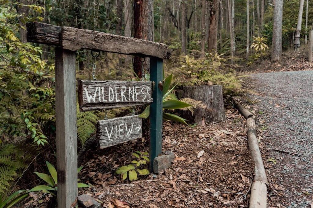 um sinal no lado de um trilho na floresta em Wilderness View em Mooloolah