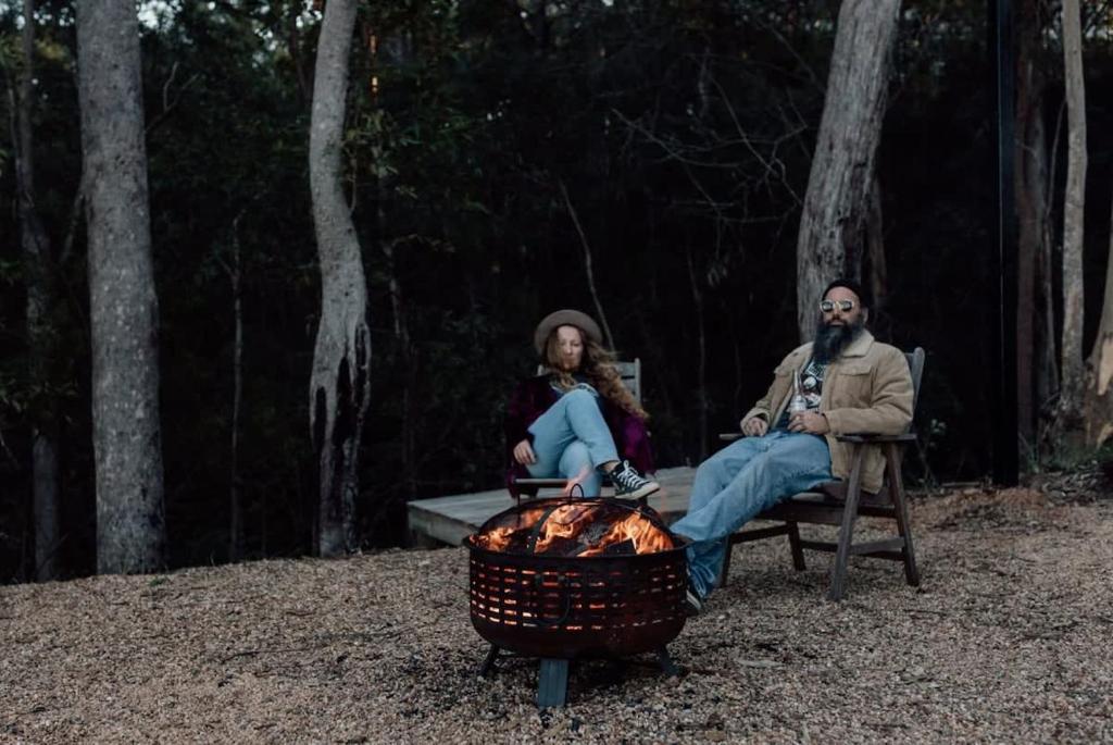 a man and woman sitting on a bench next to a fire at Tiny Tamborine 2 in Wongawallan