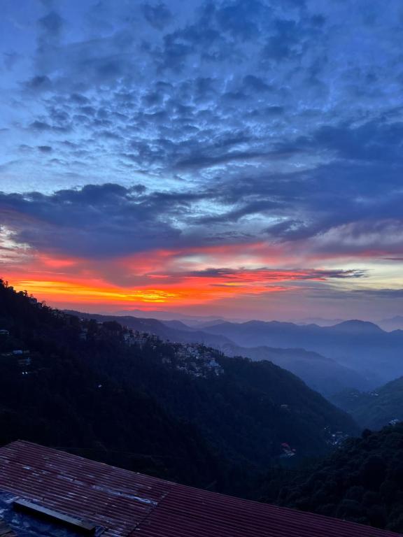 ein Blick auf einen Sonnenuntergang von einem Berg in der Unterkunft Mountain cottage in Shimla
