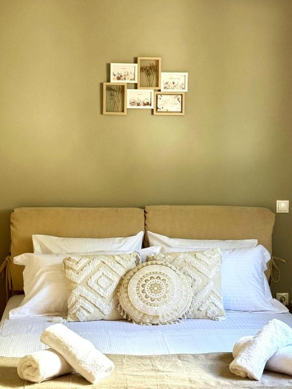 a bed with white pillows and pictures on the wall at Villa Korina in Posidhonía
