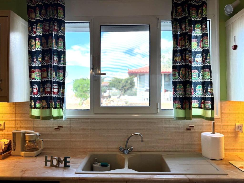 eine Küchenspüle vor einem Fenster in der Unterkunft Villa Korina in Posidhonía