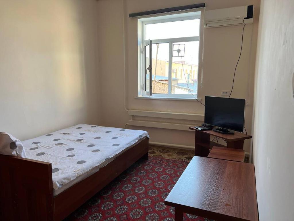 Schlafzimmer mit einem Bett, einem Schreibtisch und einem Fenster in der Unterkunft Guest House Medic in Nukus