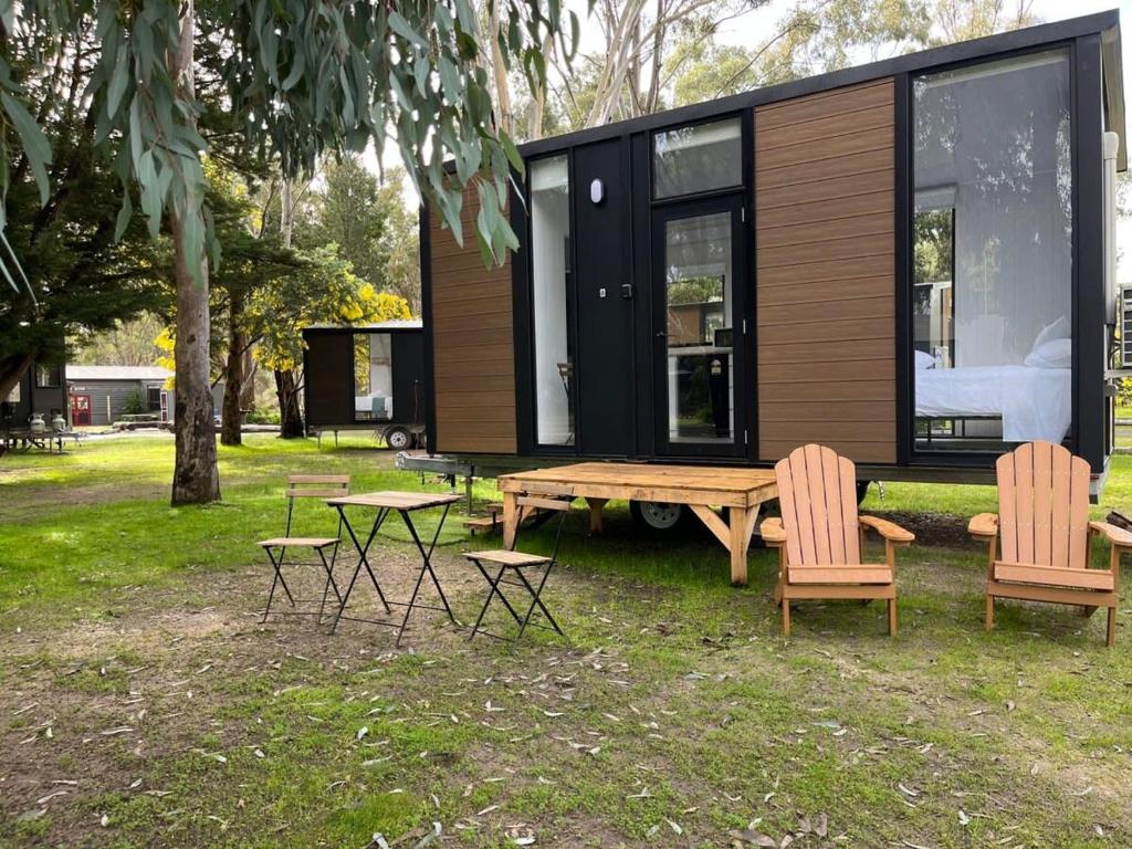 a tiny house with a wooden table and chairs at Tiny House 8 at Grampians Edge in Dadswells Bridge