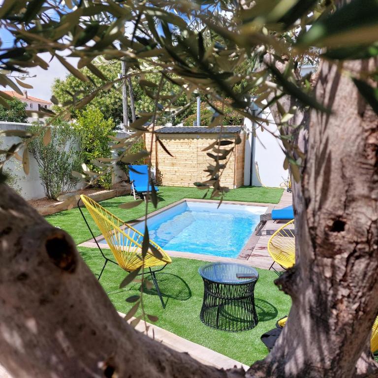 une cour avec une piscine, des chaises et un arbre dans l'établissement Maison familiale avec jacuzzi et piscine, à La Rochelle