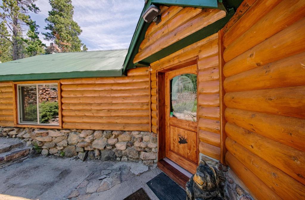 een hut met een deur en een stenen muur bij Longs Peak Cabin - Monthly Long-Term Vacation Rental 30 Days -- Estes Park cabin in Allenspark