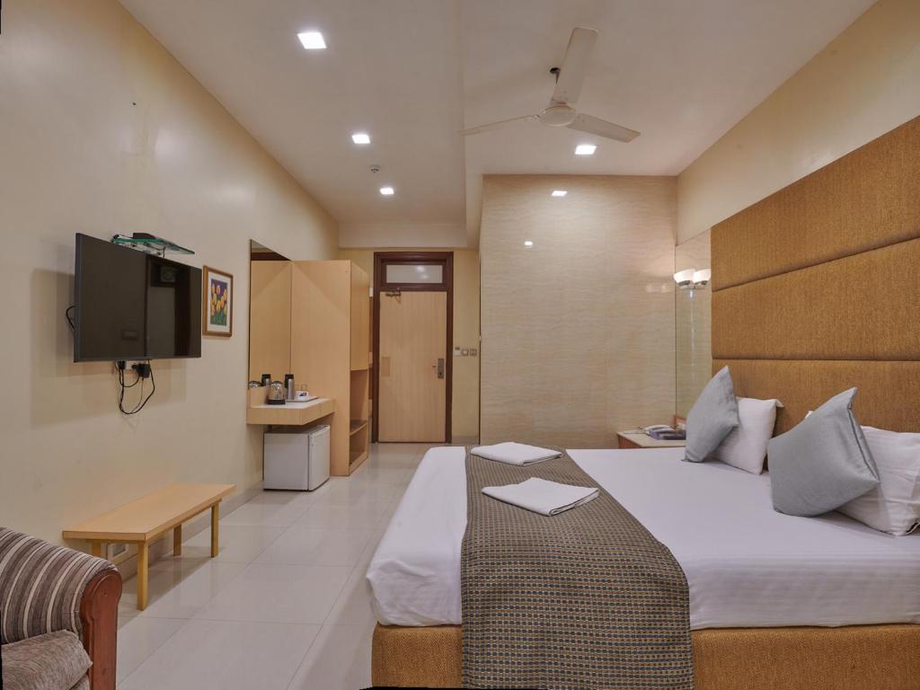 een hotelkamer met een bed en een televisie bij Bentley Hotel, Marine Drive in Mumbai