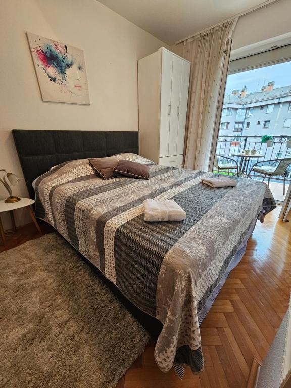 a bedroom with a large bed and a large window at Apartman Sany in Bihać