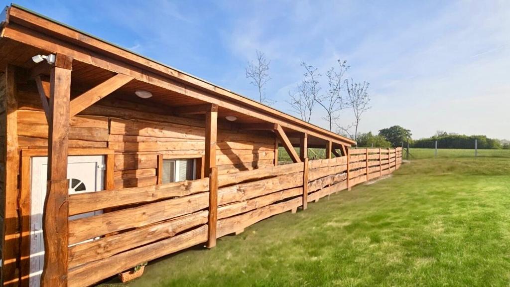 ein Holzhaus mit einem langen Zaun auf einem Feld in der Unterkunft MBL Apartments Summer in Rezi