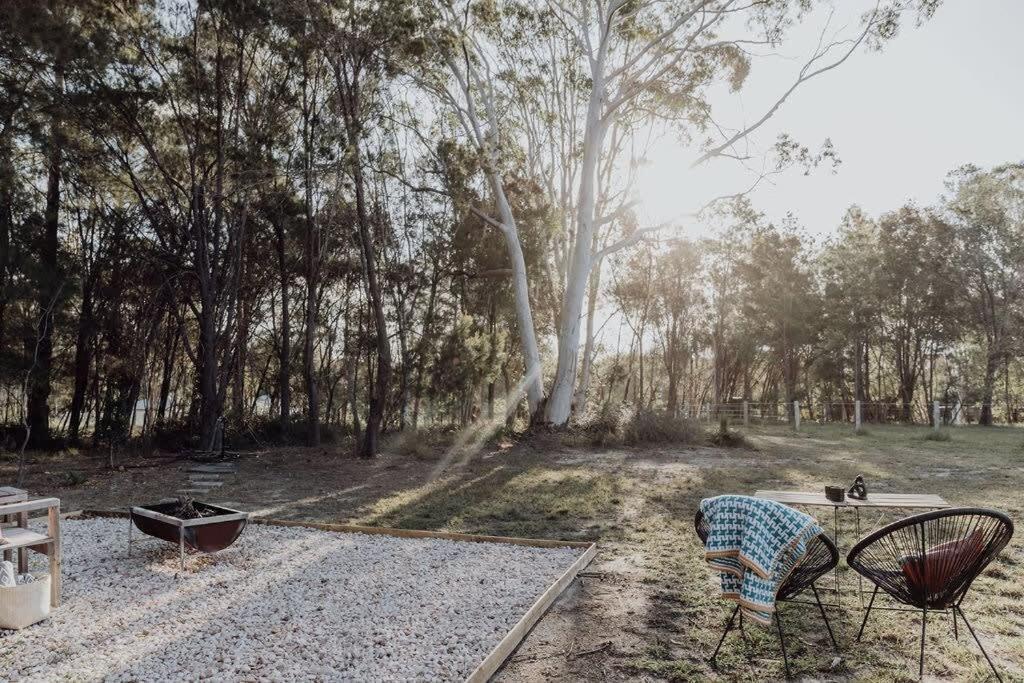 um parque com duas cadeiras, uma mesa e árvores em Noosa Tiny Home em Ringtail Creek