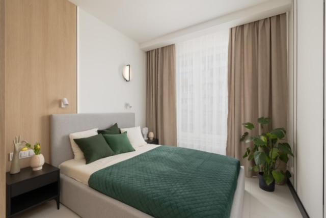 sypialnia z łóżkiem z zieloną pościelą i oknem w obiekcie JTB Brama Portowa w Szczecinie