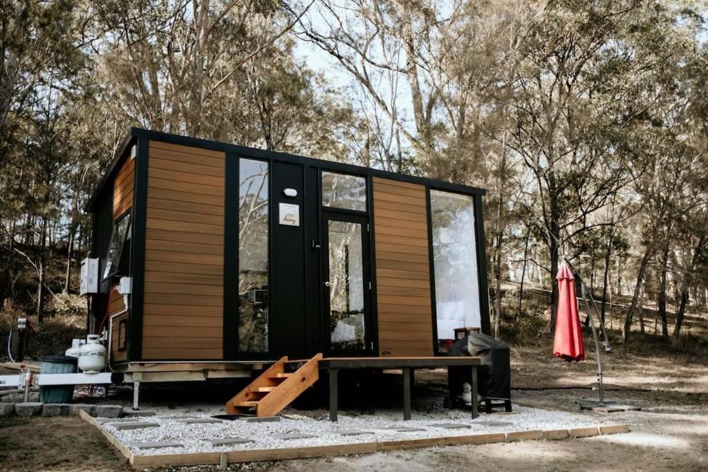 a tiny house with a bench and an umbrella at Hidden Creek Tiny Home in Kurrajong