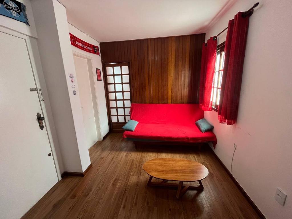 een woonkamer met een rode bank en een tafel bij Studio Grenal - JK Bem Localizado in Porto Alegre