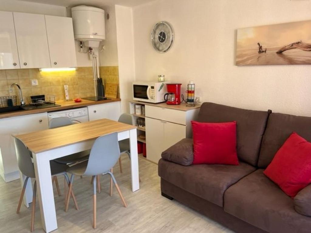 - un salon avec un canapé et une table avec des oreillers rouges dans l'établissement Appartement Rénové avec Clim, Parking, Piscine—Proche Commerces, Plage et Port au Cap d'Agde - FR-1-749-6, au Cap d'Agde