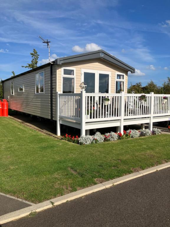 a tiny house with a white fence and flowers at Miss Grace Plot 26 in Lincoln