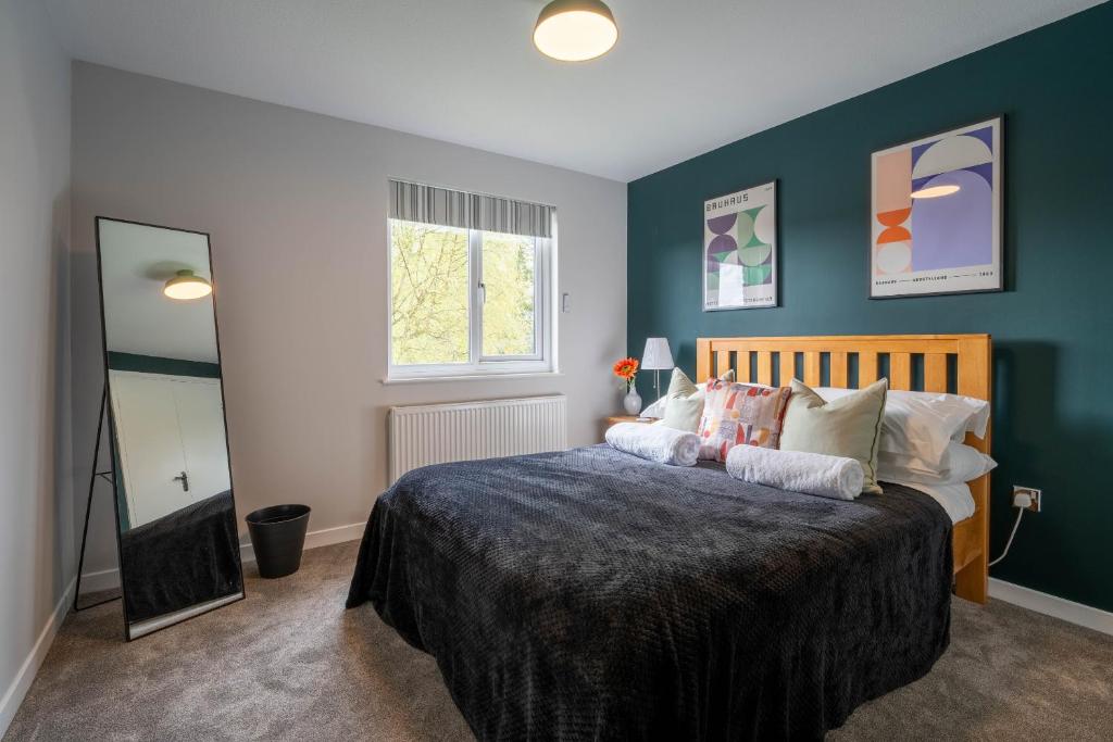 una camera da letto con un grande letto con pareti blu di Park View- 2 bed apartment close to East Surrey Hospital a Salfords