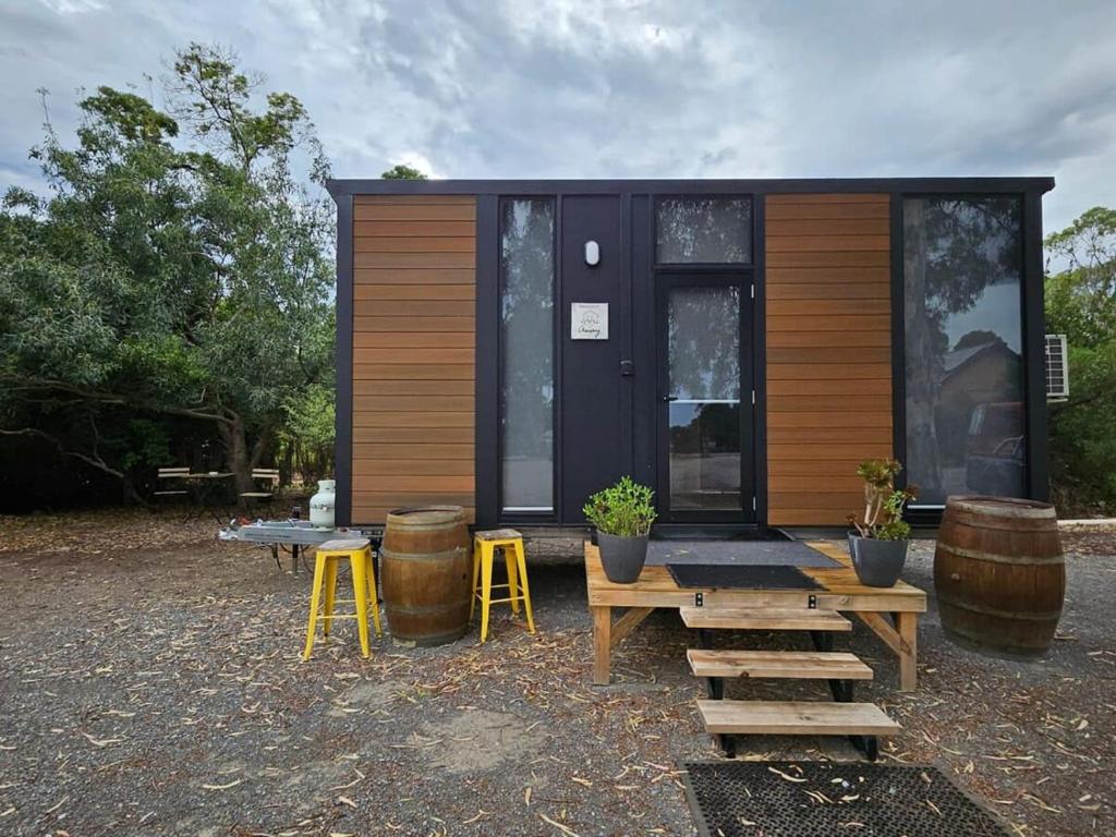een tiny house met een picknicktafel en krukken bij Alma's Tiny House in Willunga