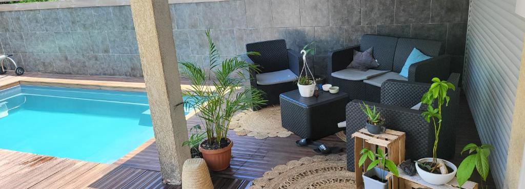 einen Hinterhof mit einem Pool und einer Terrasse mit Pflanzen in der Unterkunft La villa Loca Reunion in Saint-Joseph