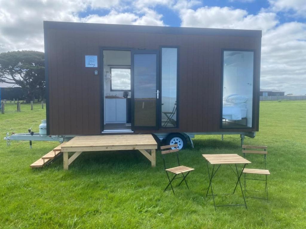 una casa pequeña con mesa de picnic y 2 sillas en Lough View Cabin, en Rosecrook