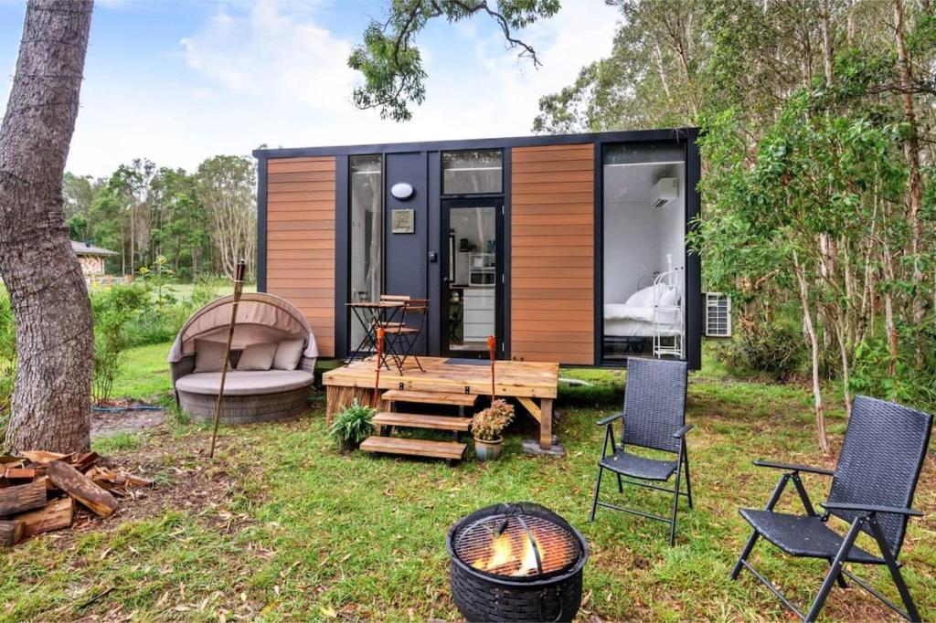 una pequeña casa en el bosque con una mesa y sillas en Clarence Farm Stay, en Maclean