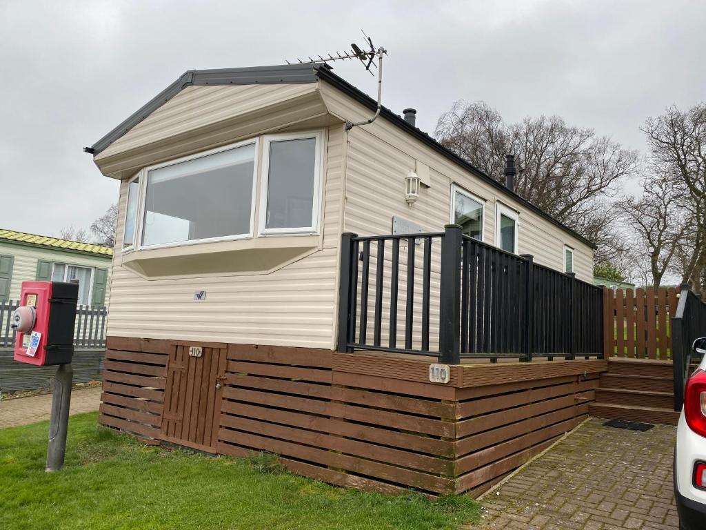 una piccola casa con una recinzione in legno nel cortile di Caravan SK 110 a Leven-Fife