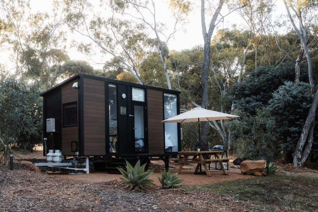 a tiny house with a picnic table and an umbrella at Djindarup Retreat 1 in Prevelly