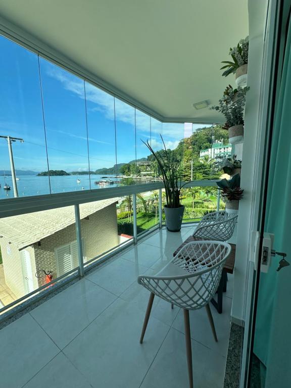 a balcony with chairs and a table and a view of the ocean at Praia Grande, Angra dos Reis in Angra dos Reis